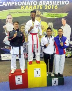 O atleta Lucas Elloi dos Santos no 3º lugar do pódio da categoria Luta Masculino 60 kg (de casaco branco) Foto: divulgação/PMI.